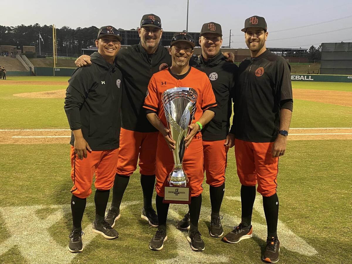 The Huntington Beach baseball coaching staff, including head coach Benji Medure, center, poses with the championship trophy.