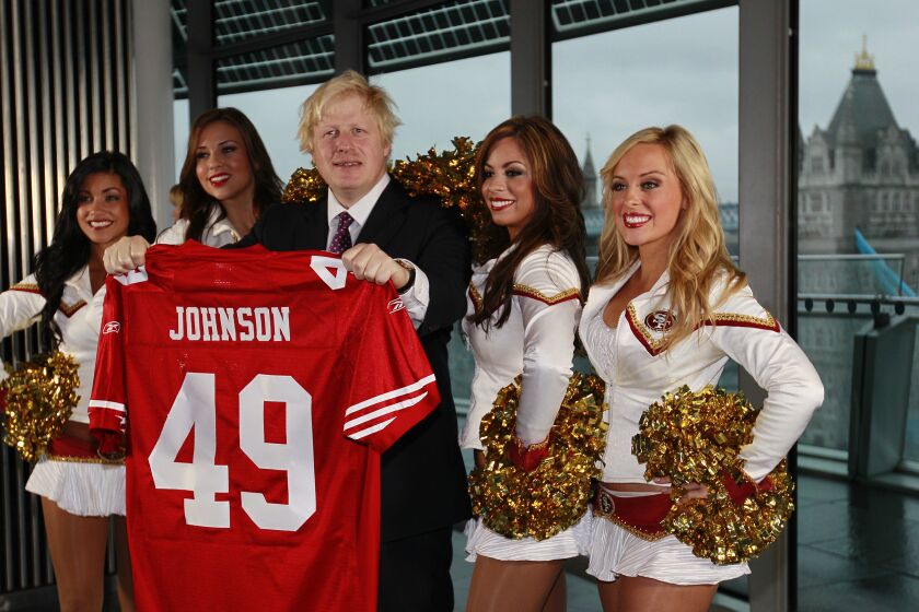 FILE - Boris Johnson, then Mayor of London center, and four of the 49ers cheerleaders Deanna Ortega, left, Morgan McLeod, Alexis Kofoed and Lauren Riccaboni, right, pose for the media as the Mayor holds a team shirt with his name on at City Hall in London Tuesday, Oct., 26, 2010. British media say Prime Minister Boris Johnson has agreed to resign on Thursday, July 7 2022, ending an unprecedented political crisis over his future. (AP Photo/Alastair Grant, File)
