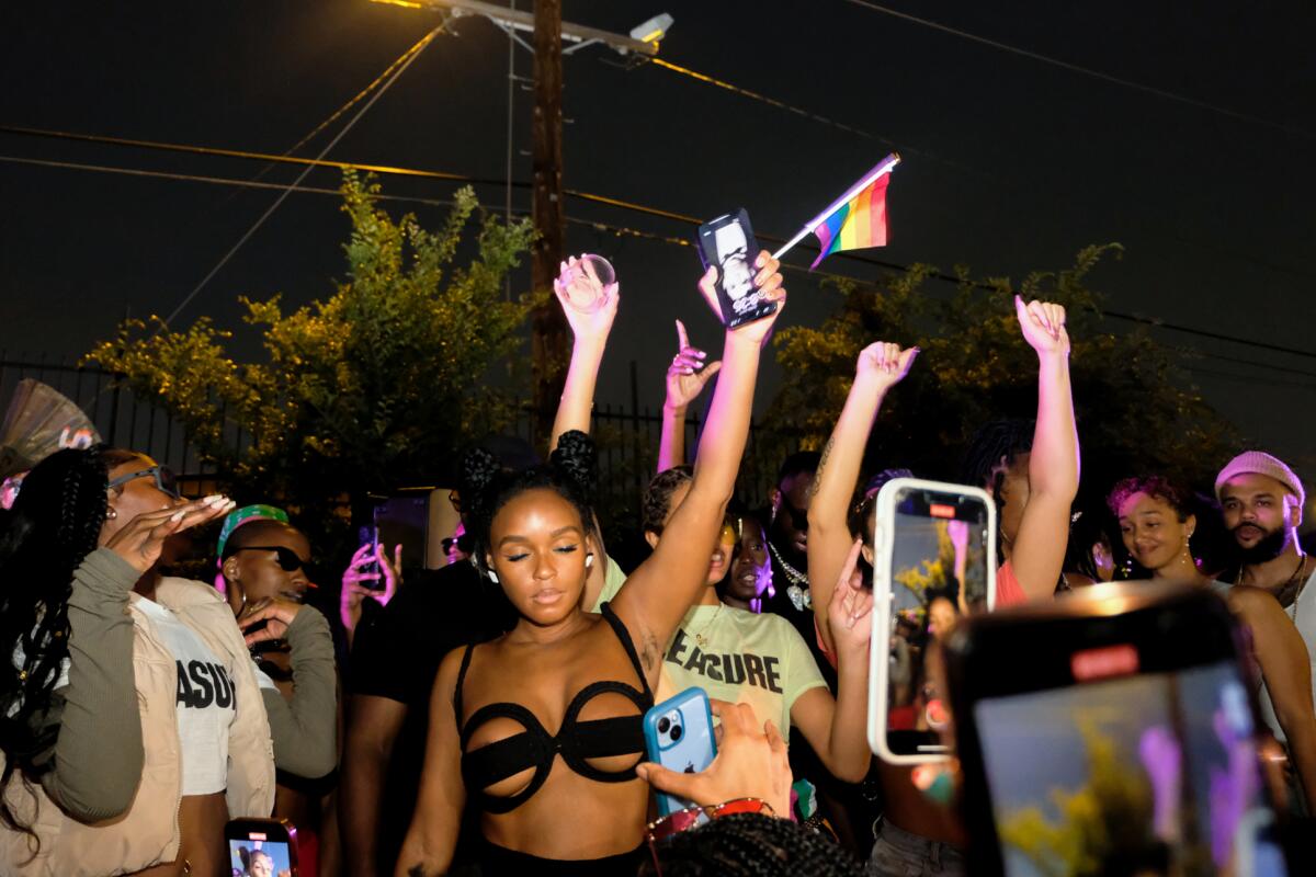 Janelle Monae dances with her eyes closed with a Pride flag in her hand at an Everyday People party. 
