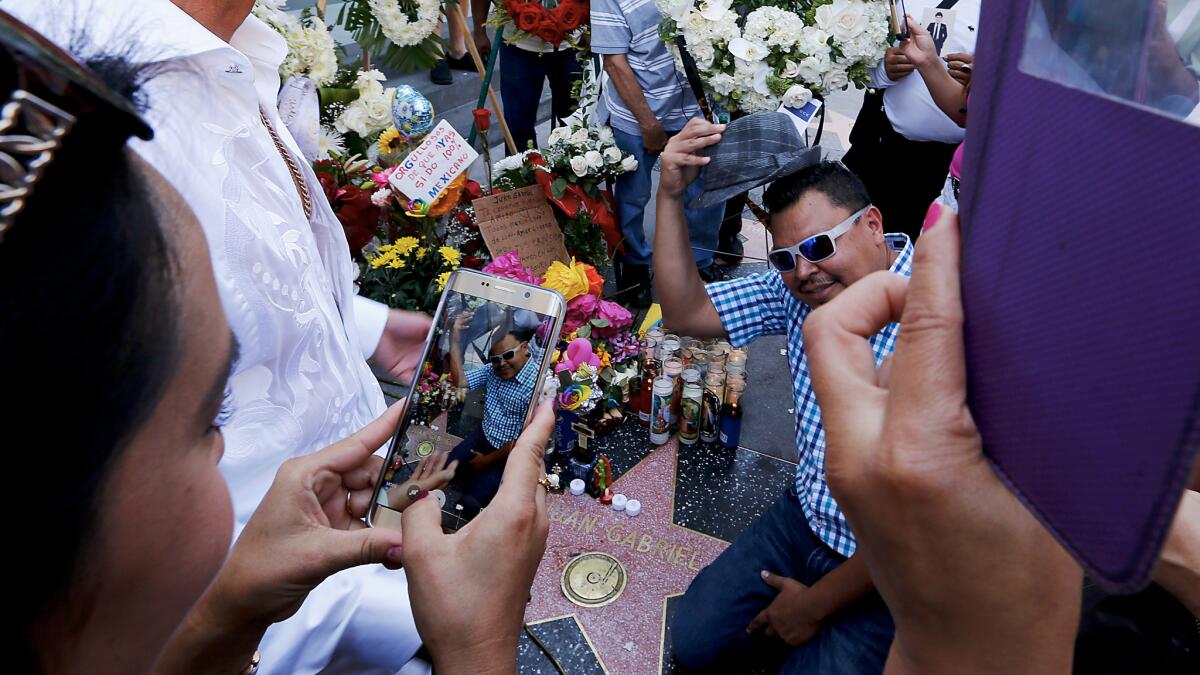 Fans of Mexican pop singer/songwriter Juan Gabriel take selfies at his star on the Hollywood Walk of Fame, which was turned into an impromptu memorial.