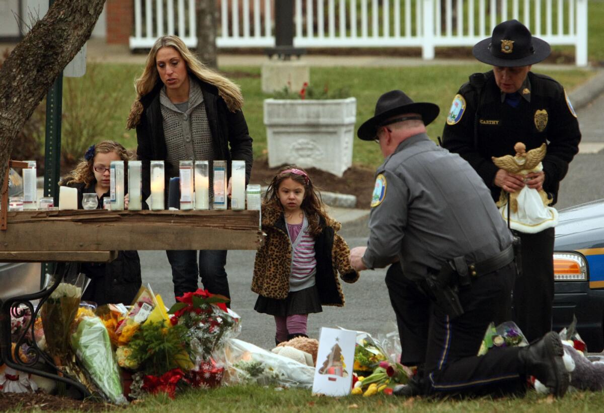 Two days after the 2012 shooting at Sandy Hook Elementary School in Newtown, Conn., a pair of Newtown police officers tend a makeshift memorial at St. Rose of Lima Church.