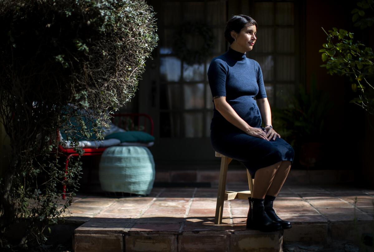 Poet Megan Dorame sits at her home.  