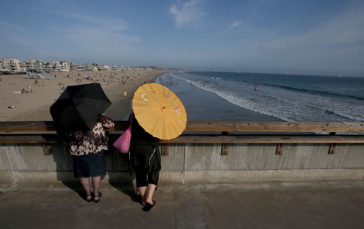 Two women look over the south side of the Venice Beach Pier.