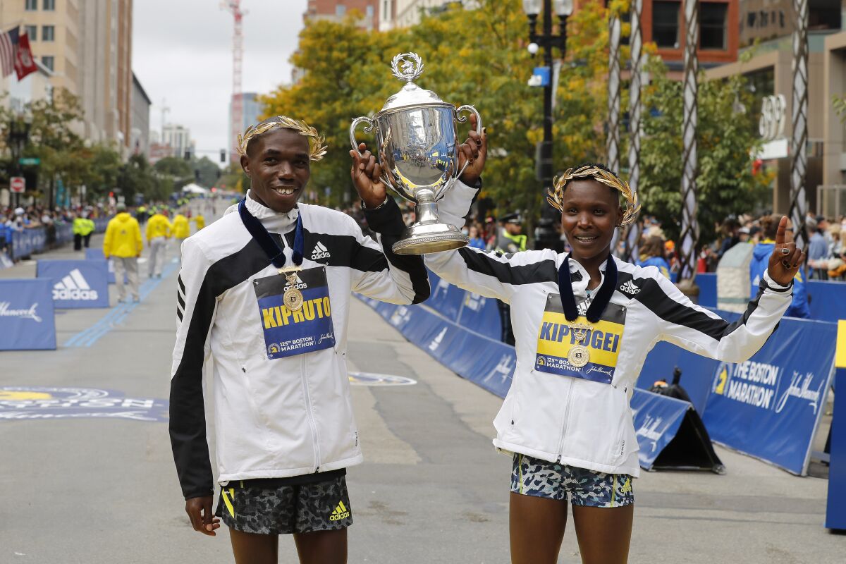 Benson Kipruto, left, and Diana Kipyogei, both of Kenya, celebrate winning the men's and women's divisions of the 125th Boston Marathon on Monday, Oct. 11, 2021, in Boston. (AP Photo/Winslow Townson)