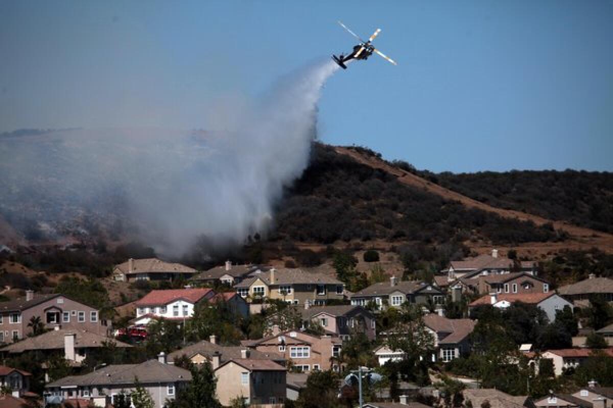 A helicopter douses a fire near Camarillo Springs that was fueled by Santa Ana winds and warm temperatures.