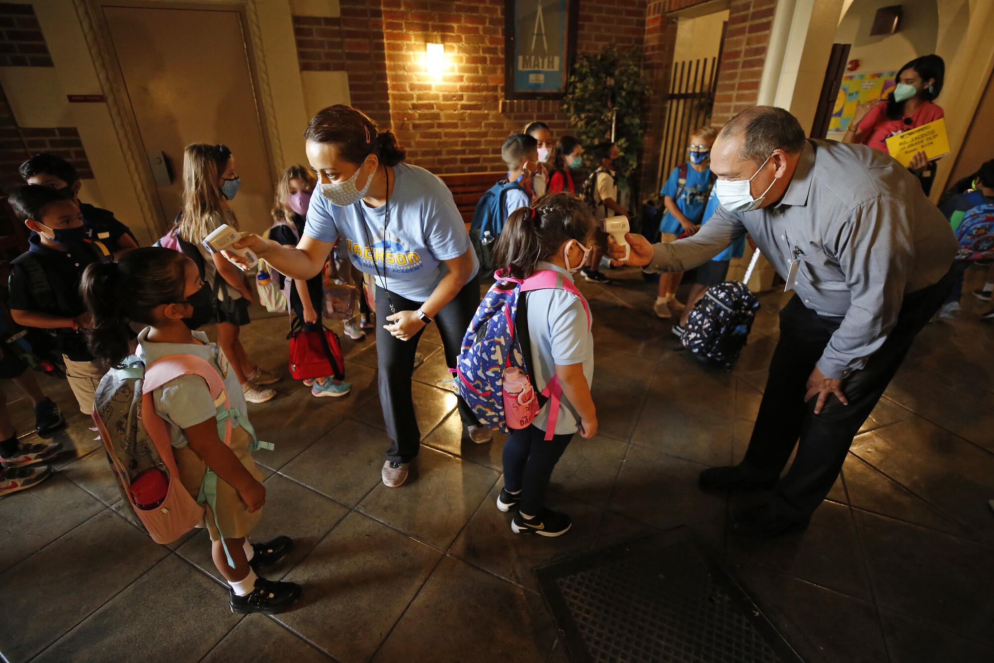 Aurora Flores, left, and Rene Saldivar take the temperature of students.