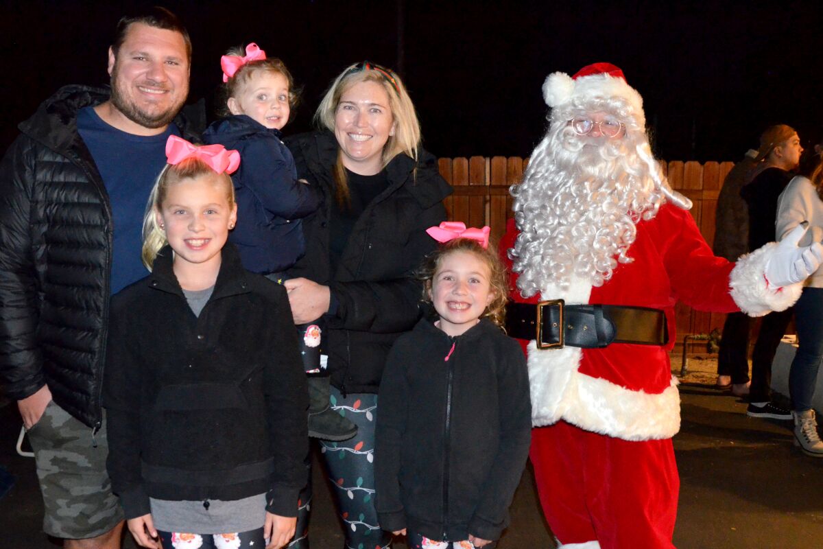 Santa poses with the Doyle family who won Best Theme, "SantaGoneFishing," for the Costa Mesa Home Decorating Contest.