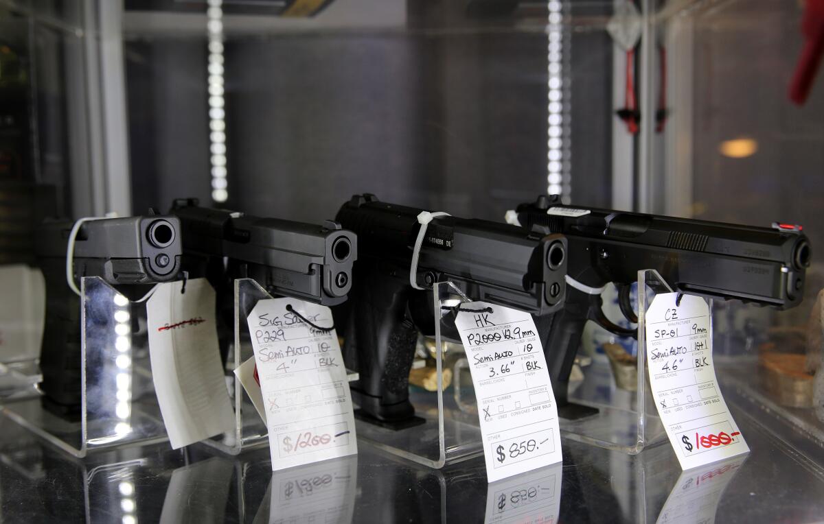 Guns for sale standing in a glass case. 