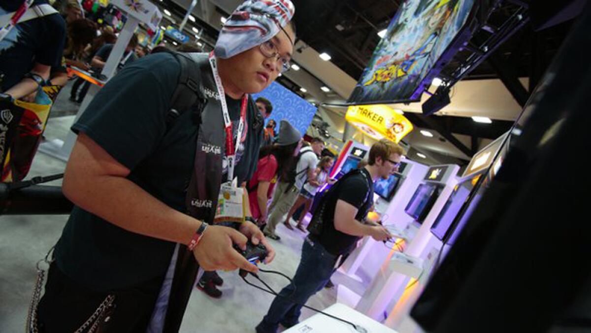 Richard Soukharivong plays the video game "Godzilla" on opening day of Comic-Con 2015.