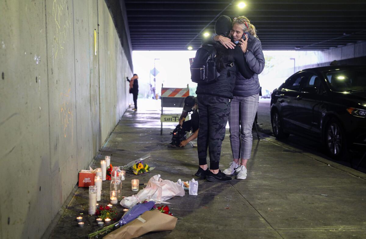 Amie Zamudio and Nina Hermosura embrace in front of a make-shift memorial under the City College bridge on Monday.