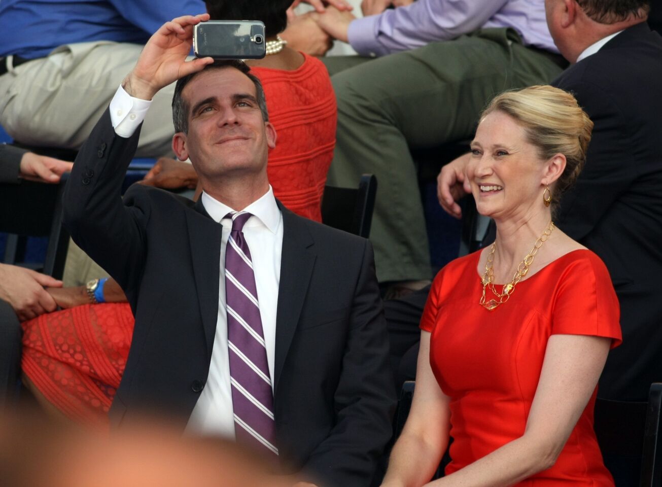 Eric Garcetti shoots video of proceedings seated next to his wife, Amy Wakeland, after being sworn-in.