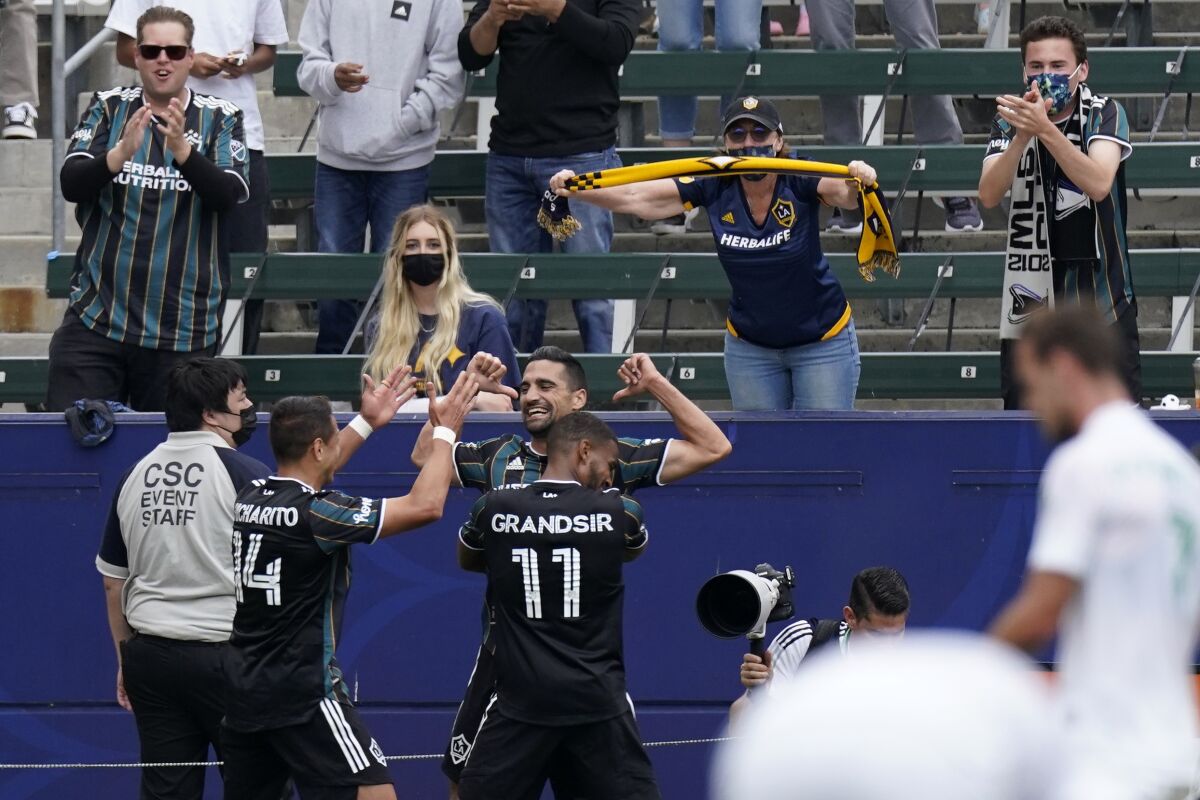 Galaxy midfielder Sebastian Lletget celebrates with teammates Samuel Grandsir and forward Javier “Chicharito” Hernández.
