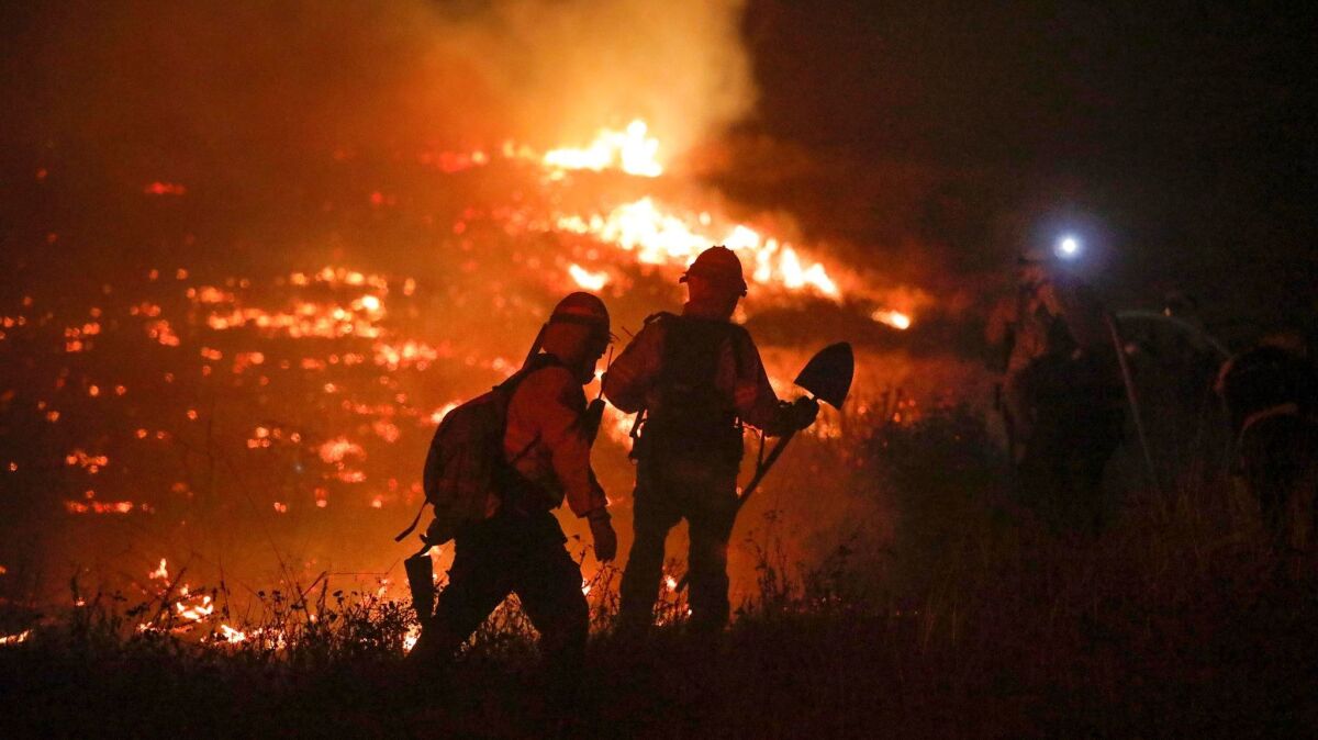Firefighters battle the Lilac Fire along West Lilac Road on Dec. 7. The California Public Utilities Commission passed more stringent fire safety rules, citing concerns of greater wildfire risk in the state.