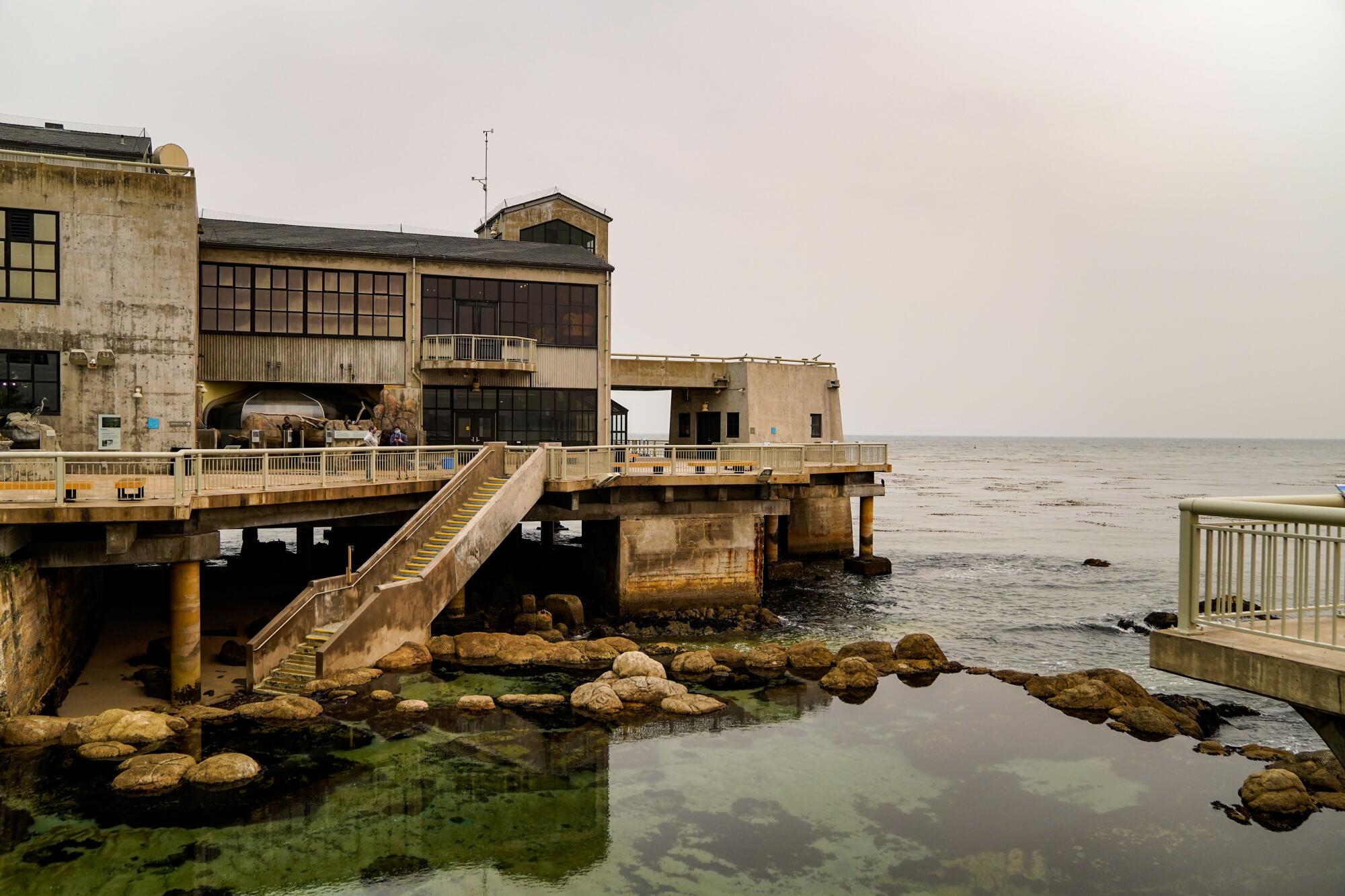 The old, weathered building housing Monterey Bay Aquarium on Cannery Row looks out over the water