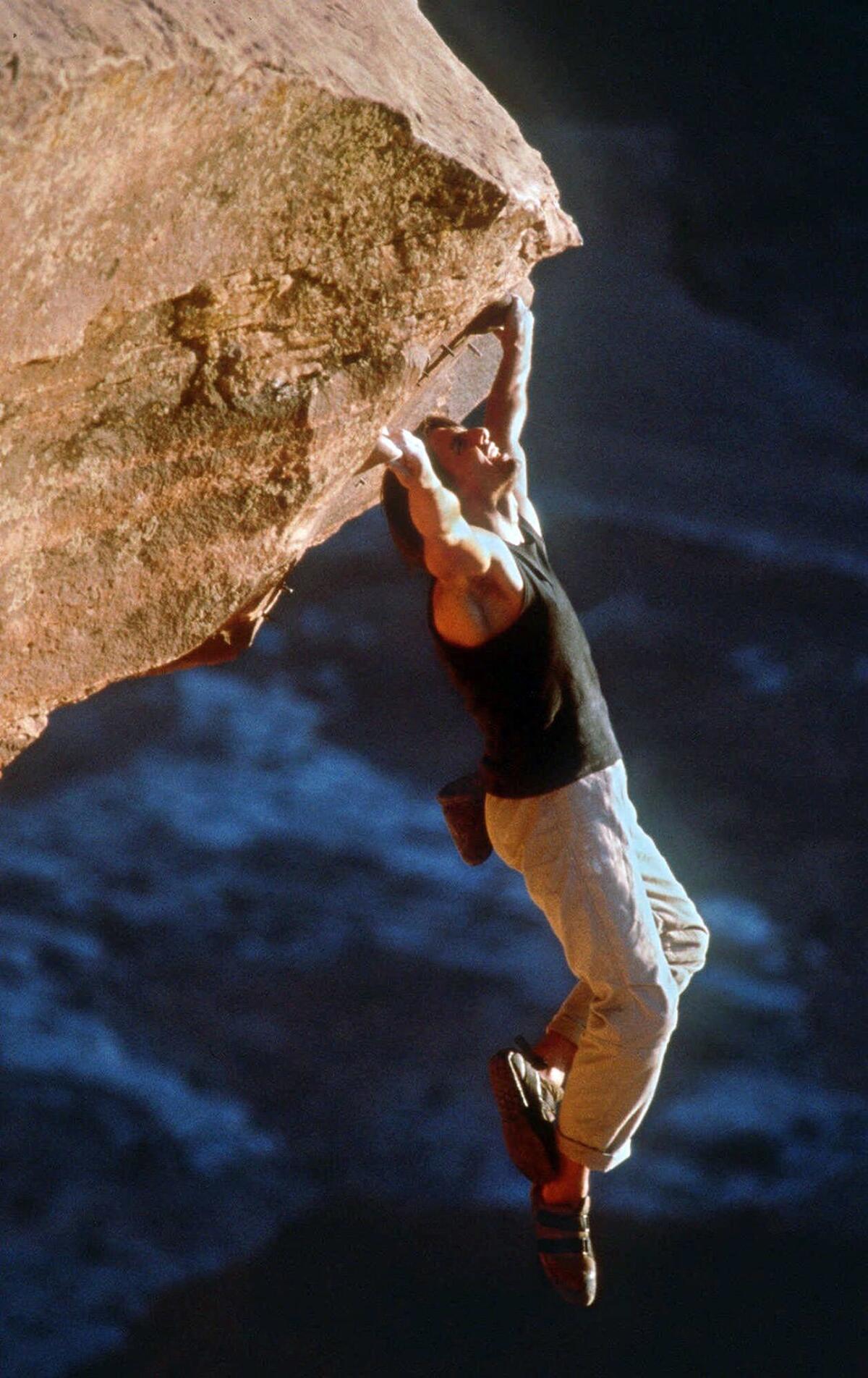 Tom Cruise hangs from a cornice while mountain climbing in a scene from the film "Mission: Impossible 2."