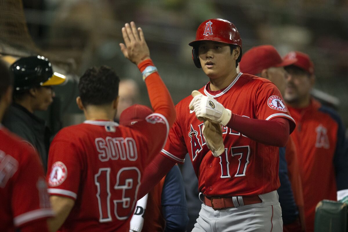 Angels designated hitter Shohei Ohtani is greeted by his teammates after scoring on a double from Taylor Ward.