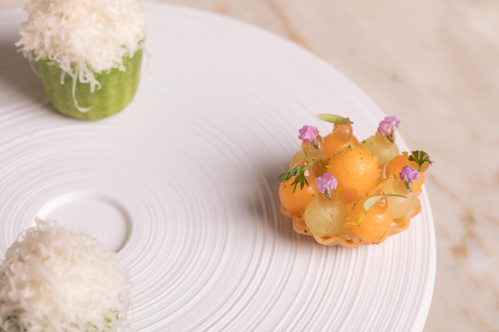 Summer melon canapé on a white plate with white crab in a green tart shell