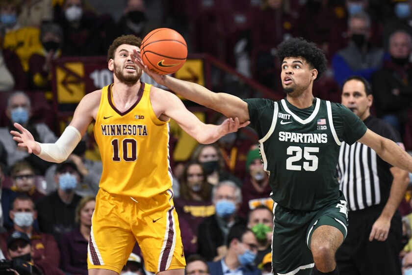 Michigan State guard Malik Hall (25) reaches for a rebound before Minnesota forward Jamison Battle can get to it during the first half an NCAA college basketball game Wednesday, Dec. 8, 2021, in Minneapolis. (AP Photo/Craig Lassig)