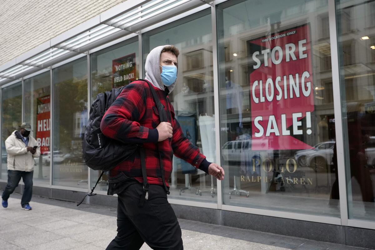 A man walks past a sign in a store window that says: "store closing sale"