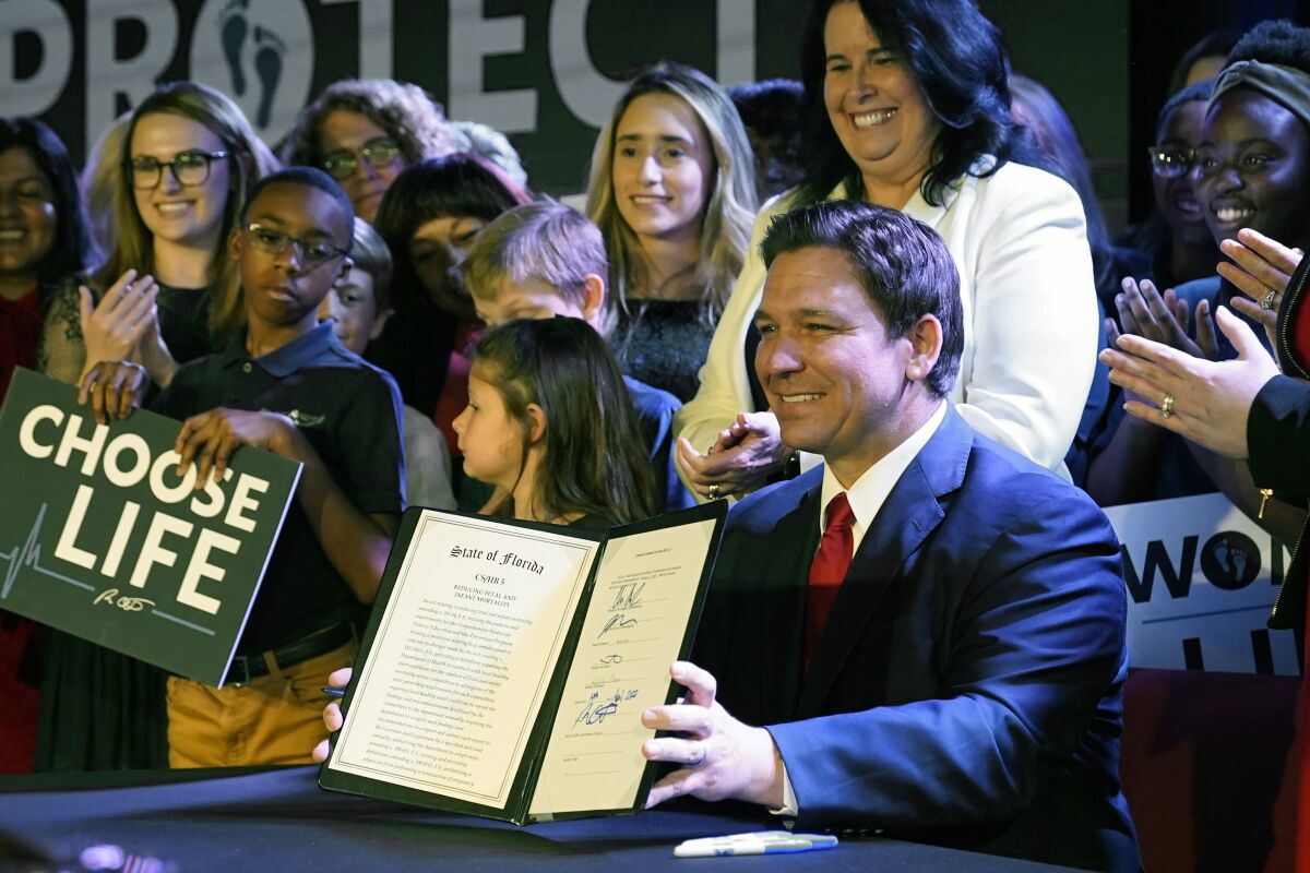 FILE - Florida Gov. Ron DeSantis holds up a 15-week abortion ban law after signing it on April 14, 2022, in Kissimmee, Fla. A synagogue claims in a lawsuit filed Friday, June 10, 2022, that a new Florida law prohibiting abortion after 15 weeks violates religious freedom rights of Jews in addition to the state constitution’s privacy protections. (AP Photo/John Raoux, File)