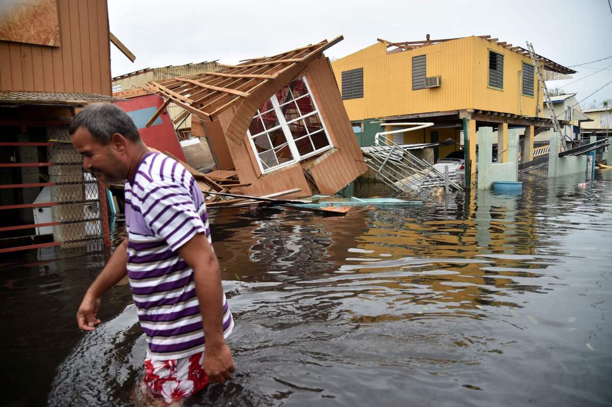 A man walks past a house laying in flood water in Juana Matos, Puerto Rico, after the U.S. territory was pummeled by Hurricane Maria in September.