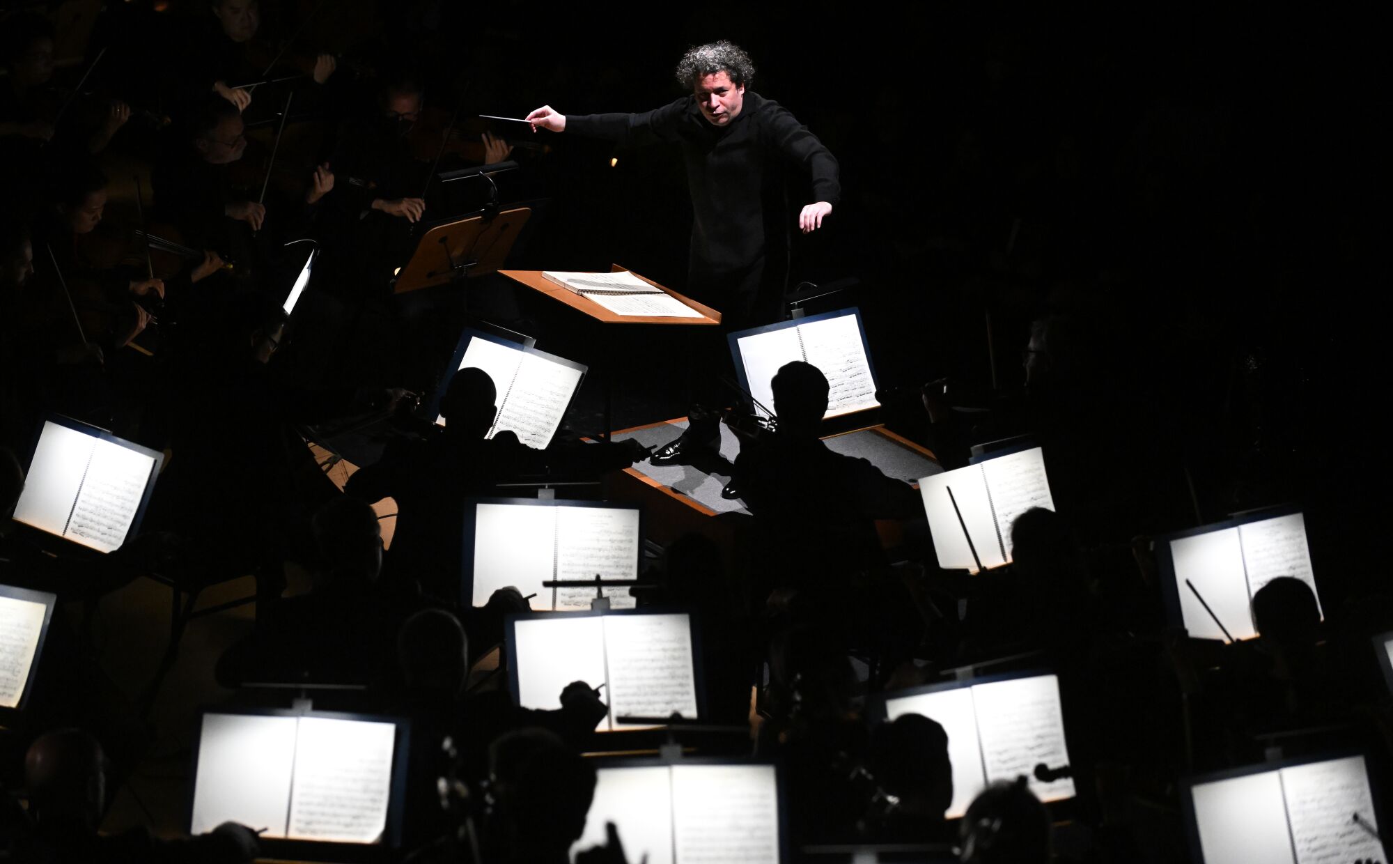 Vu dans la partie supérieure du cadre sur fond noir, Gustavo Dudamel dirige l'orchestre ci-dessous.