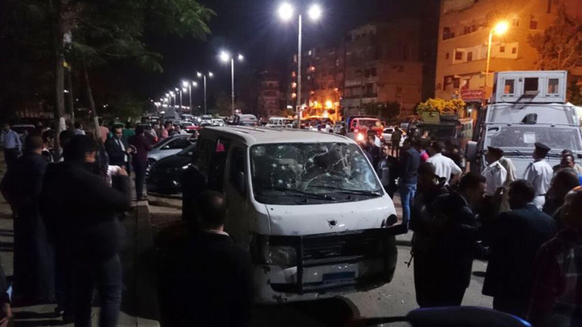 Egyptian police and civilians gather around a bullet ridden microbus in the south Cairo neighborhood of Helwan.