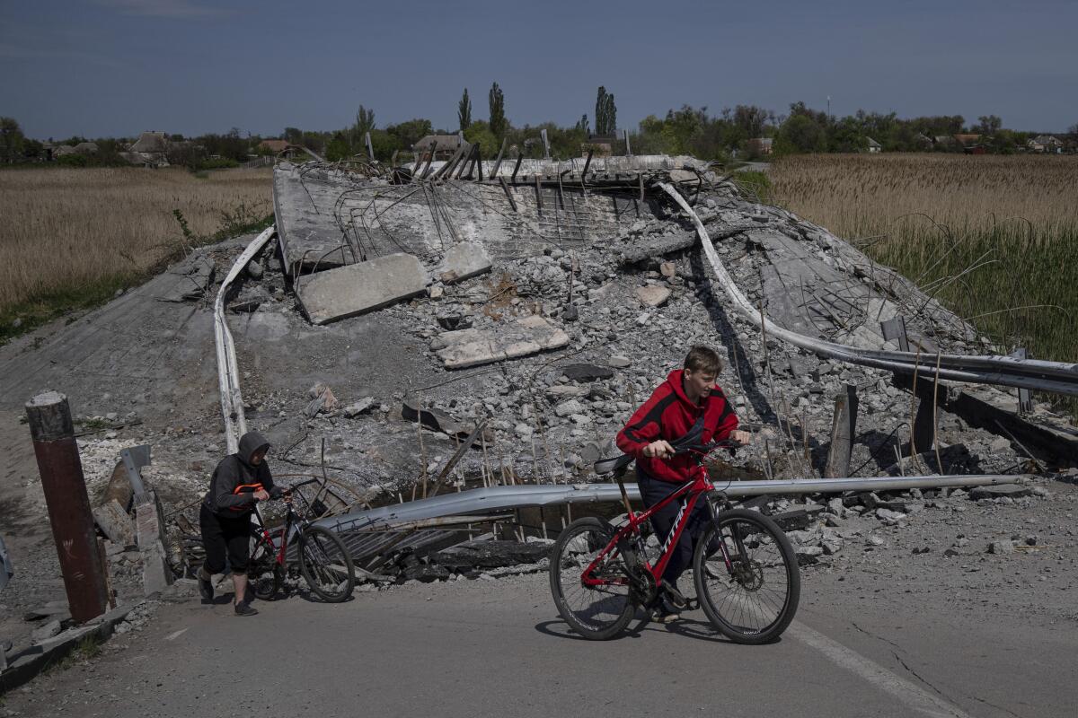 Dos adolescentes pasan en bicicleta por un puente destruido cerca de Orihiv, Ucrania, el 5 de mayo de 2022.