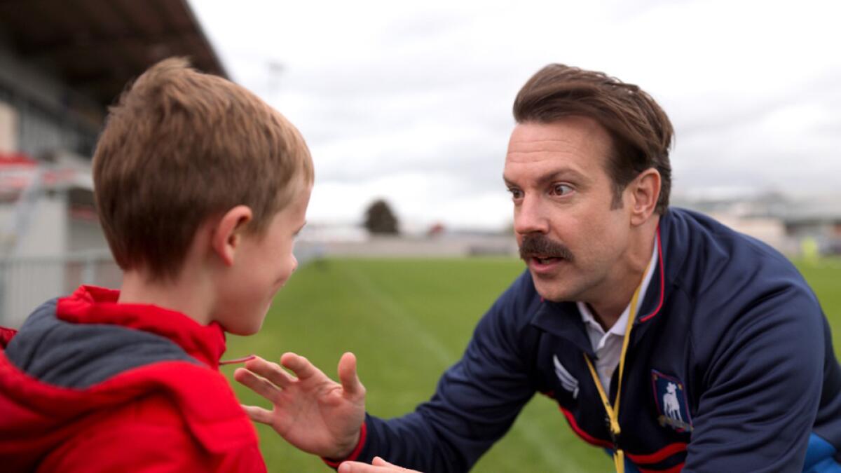 A man squats down to talk with a little boy