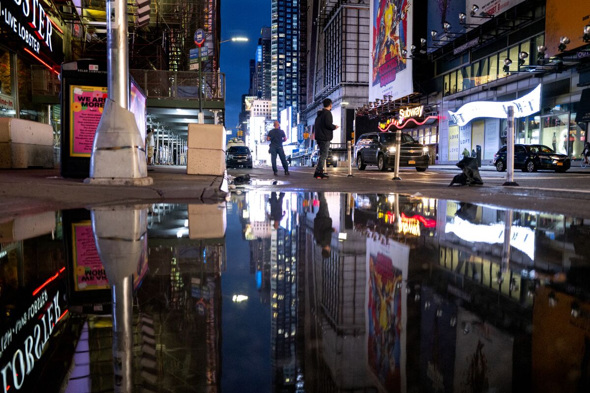 The lights of Times Square in New York are reflected in standing water after flooding.
