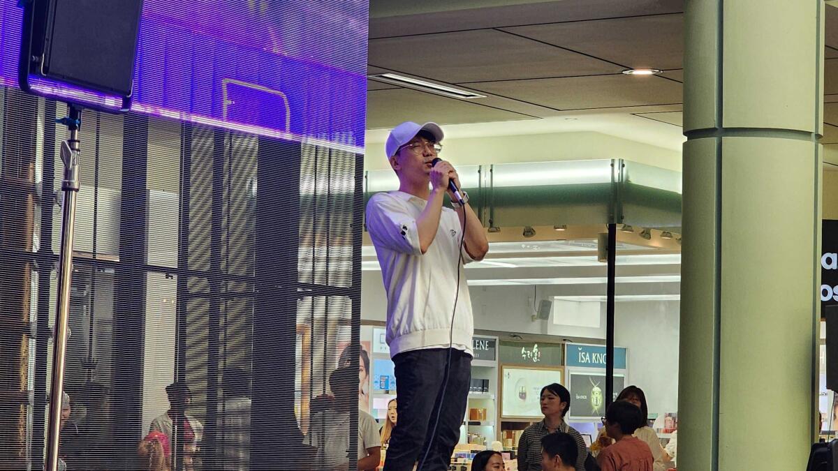 A man in a baseball cap sings karaoke onstage.