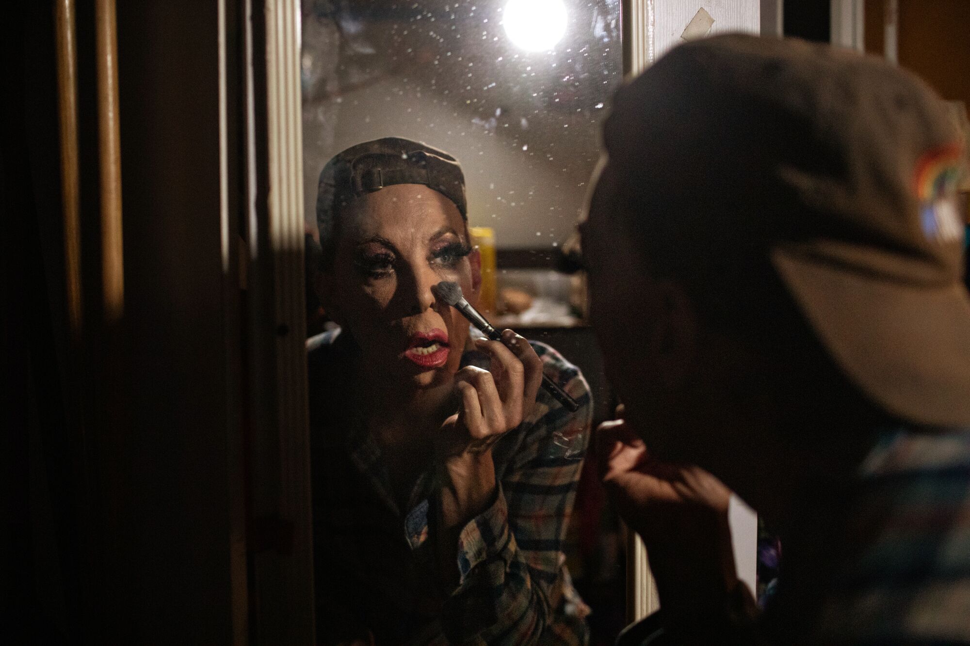 An actor blends makeup with a brush.