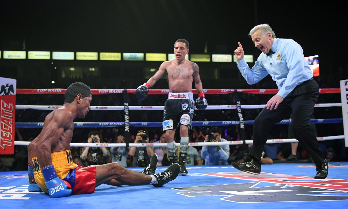 Miguel Marriaga, left, of Colombia, sits on the canvas after being knocked down by Oscar Valdez, Jr., center, of Mexico, as referee Jack Reiss give him a count during the 10th round of a WBO featherweight world championship bout, Saturday, April 22, 2017, in Carson, Calif. (AP Photo/Mark J. Terrill)