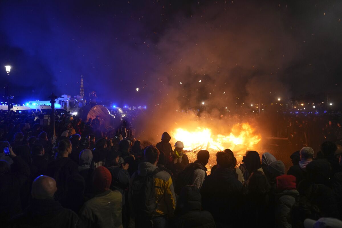 Demonstrators gather next to a burning barricade in Paris.