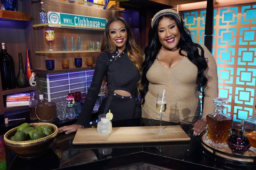 Two women posing behind a bar on a TV set