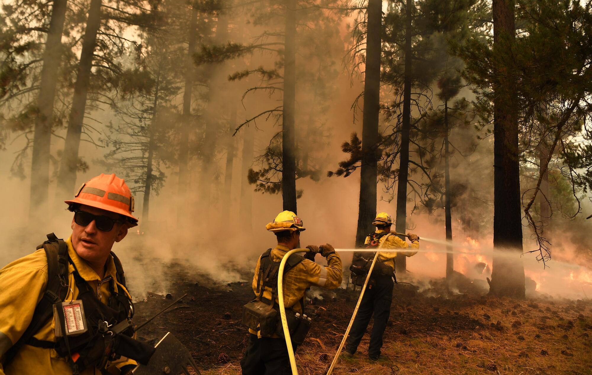 Firefighters spray hoses at the Caldor fire.