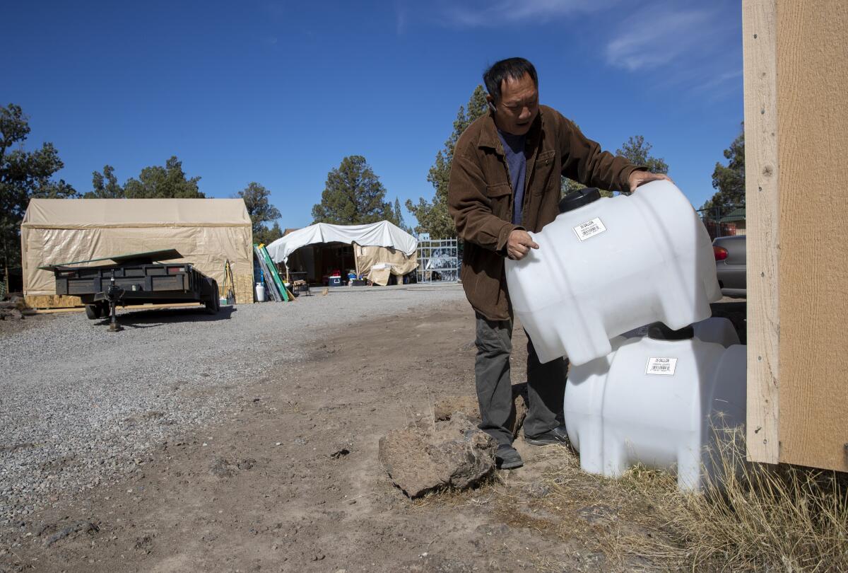 A man stacks portable water tanks.