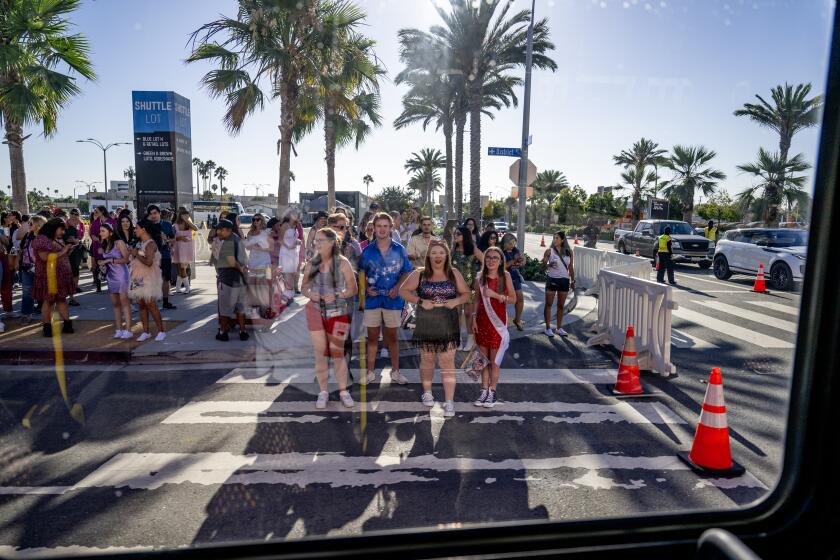 INGLEWOOD, CA - AUGUST 3, 2023: Framed through a shuttle bus window, Taylor Swift fans wait at a cross walk to get to SoFi Stadium to attend Taylor Swift Eras SoFi Stadium tour concert on August 3, 2023 in Inglewood, California. (Gina Ferazzi / Los Angeles Times)