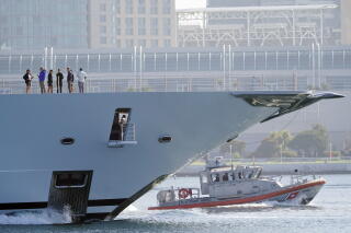 A small boat is seen beneath the bow of a large boat.