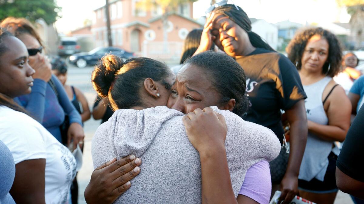 Prescious Sasser cries as she hugs a friend at a vigil for her 18-year-old son, Kenney Watkins, after he was fatally shot by police in South L.A.