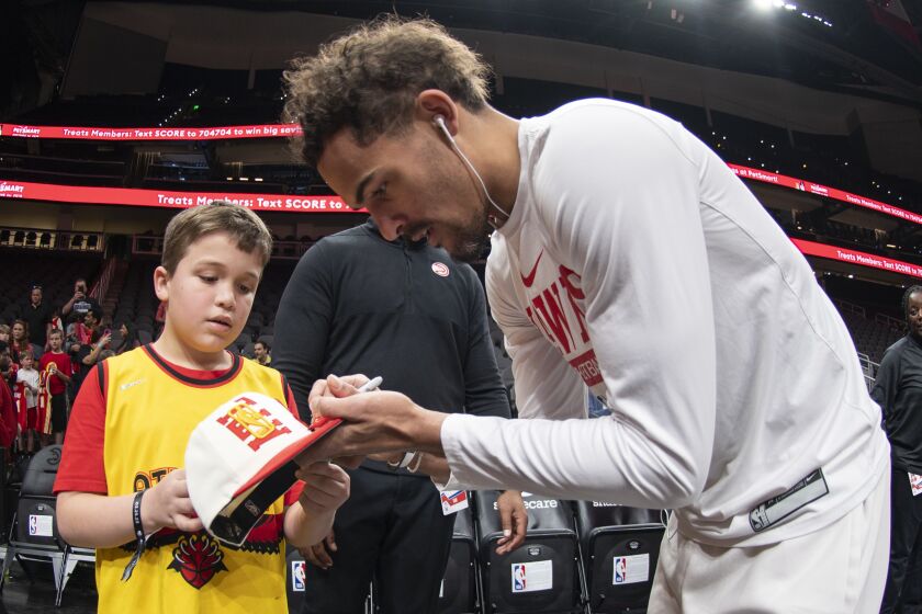 Atlanta Hawks guard Trae Young signs an autograph for a young fan before an NBA basketball game against the Indiana Pacers, Saturday, March 25, 2023, in Atlanta. (AP Photo/Hakim Wright Sr.)