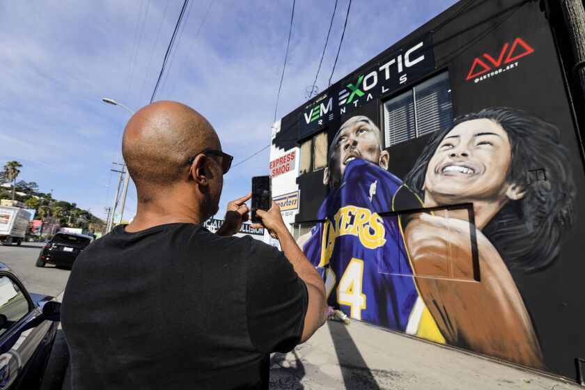 STUDIO CITY, CA - JANUARY 28, 2020 - Ryan Butler stops by to photograph a mural painted to honor Kobe Bryant and his 13-year-old daughter Gianna, who died in the helicopter crash along with seven others. Mural is painted by Art Gozukuchikyan on the side of VEM Exotic Rentals located at Ventura Blvd. in Studio City. (Irfan Khan / Los Angeles Times)