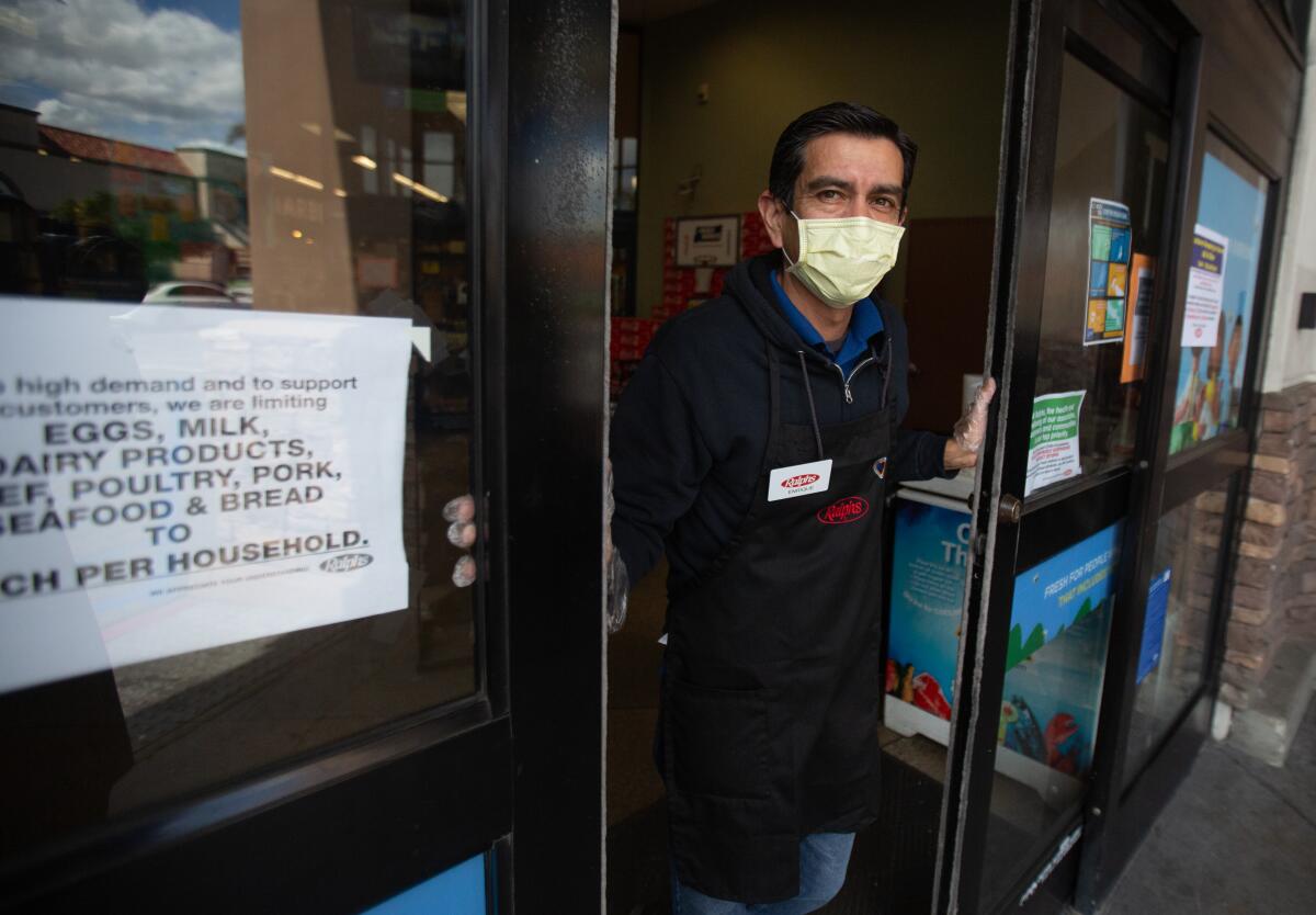 A Ralphs employee in Westchester monitors how many shoppers are allowed in at a time.