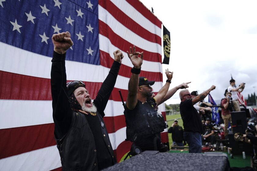FILE - In this Sept. 26, 2020 file photo, members of the Proud Boys, including leader Enrique Tarrio, second from left, gesture and cheer on stage as they and other right-wing demonstrators rally in Portland, Ore. President Donald Trump didn't condemn white supremacist groups and their role in violence in some American cities this summer. Instead, he said the violence is a “left-wing" problem and he told one far-right extremist group to “stand back and stand by.” His comments Tuesday night were in response to debate moderator Chris Wallace asking if he would condemn white supremacists and militia groups. Trump's exchange with Democrat Joe Biden left the extremist group Proud Boys celebrating what some of its members saw as tacit approval. (AP Photo/John Locher)
