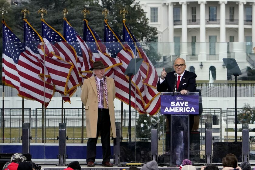 FILE - In this Jan. 6, 2021 file photo, Chapman University law professor John Eastman stands at left as former New York Mayor Rudolph Giuliani speaks in Washington at a rally in support of President Donald Trump, called the "Save America Rally." The law professor who spoke during President Donald Trump's Washington, D.C., rally last week before the attack on the U.S. Capitol has retired from a California university where there were demands for his ouster. The retirement of Eastman from Chapman University resulted from an agreement reached during discussions and was effective immediately, university President Daniele Struppa said in a statement to the school community Wednesday. (AP Photo/Jacquelyn Martin, File)