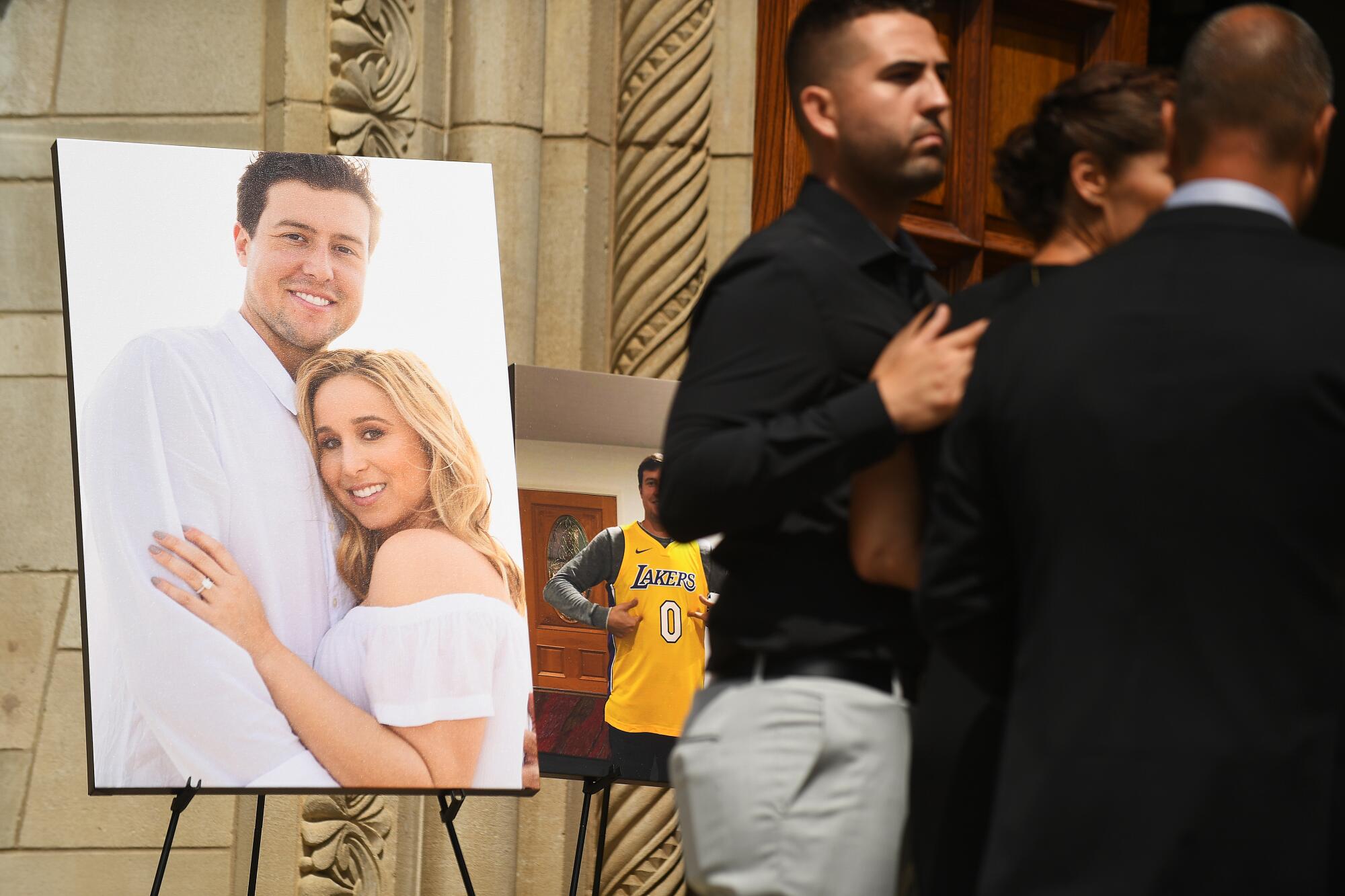 A large photo of Tyler Skaggs and his wife, Carli, is displayed on an easel beside mourners in black at a memorial service