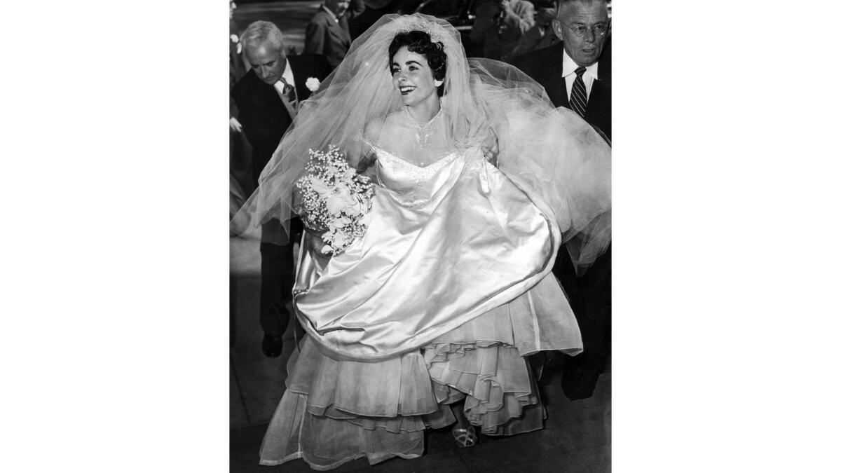 May 6, 1950: Gathering up her gown, Elizabeth Taylor enters the Church of the Good Shepherd in Beverly Hills for her marriage to Conrad "Nick" Hilton Jr.