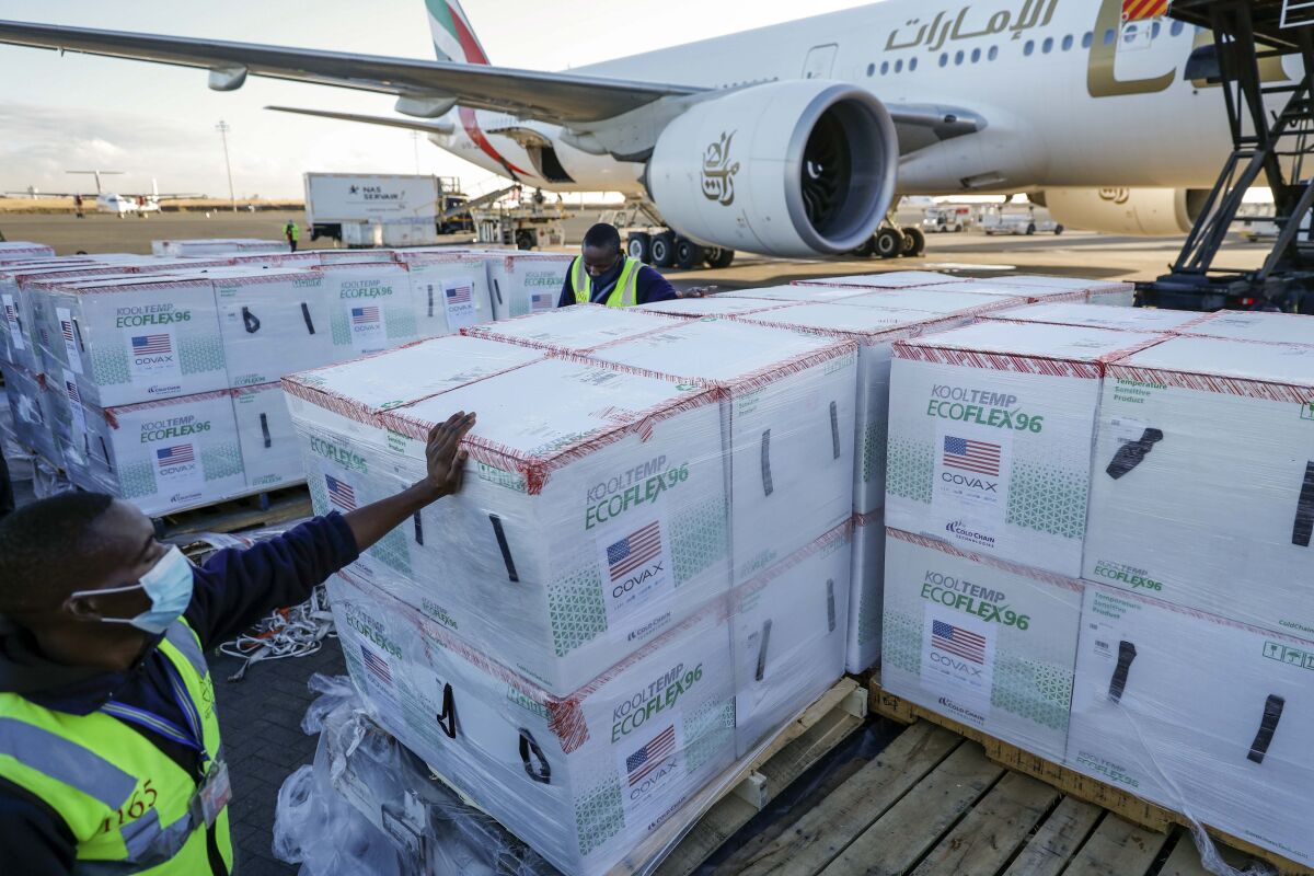 FILE - An airport worker stands next to boxes of Moderna coronavirus vaccine, donated by the U.S. government via the COVAX facility, after their arrival at the airport in Nairobi, Kenya on Aug. 23, 2021. Moderna signed a memorandum of understanding with Kenya's government on Monday, March 7, 2022 for the drugmaker's first mRNA vaccine manufacturing facility in Africa, the company said. (AP Photo/Brian Inganga, File)
