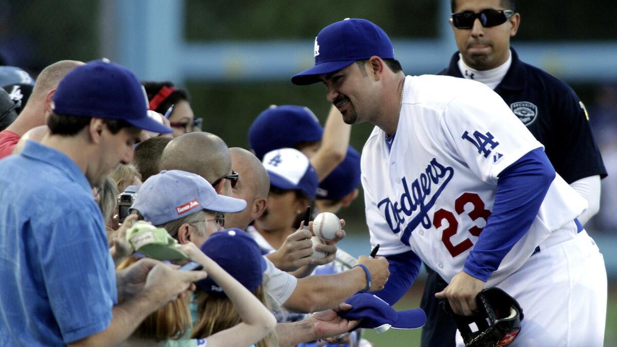 Adrian Gonzalez signs autographs for fans before a Dodgers game.