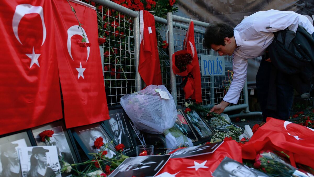 A man leaves carnations at the scene as people on Tuesday protest an attack at a popular nightclub in Istanbul.